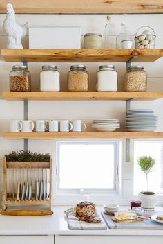 the shelves above the kitchen sink are filled with dishes and other things to cook in