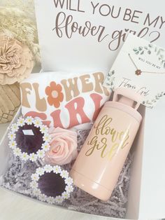 the flower girl gift box is packed with flowers, a bottle and some other items