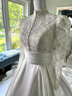 a white wedding dress on display in front of a window