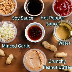 the ingredients for peanut butter are displayed in bowls on a wooden surface, including peanuts and sauces