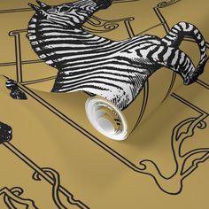 a wallpaper with zebras on it in black and gold colors, next to a coffee table