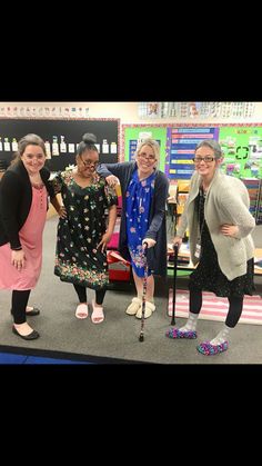 four women are standing together in front of a table with an umbrella and shoes on it