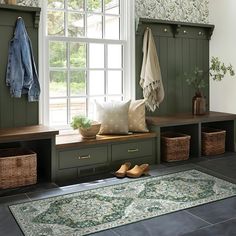 a room with green walls and wooden benches, baskets on the floor, coat rack and rug