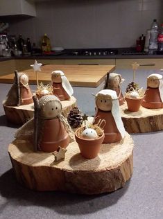 some little clay pots with angels on them sitting on a tree stump in a kitchen