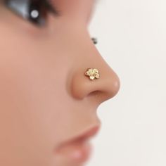 a woman's nose is shown with a small gold flower on the side of her nose