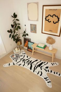 there is a zebra rug on the floor next to a table with pictures and a potted plant