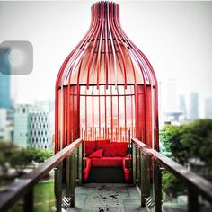 a red couch sitting in the middle of a wooden structure next to a tall building