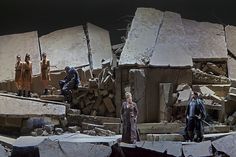 the actors are standing in front of large rocks and rubbles with one man looking at something