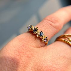 "Elegant and one-of-a-kind, this budded flower stem engagement ring features four vibrant purple-blue diamond-cut Montana sapphires. The fairy-like yet rustic twig band (cast from a real twig) comes in 100% recycled and conflict-free 14K white gold, yellow gold, or rose gold.   The organic texture seen on the band resembles the real grooves from the budded twig it is cast from, honoring the beauty of nature and flowing seamlessly around the finger. The inside is polished for a secure and comfort Purple Multi-stone Sapphire Ring, Purple Sapphire Multi-stone Rings, Tanzanite Sapphire Promise Ring With Ethical Diamonds, Purple Sapphire Ring With Rose Cut Diamonds As Gift, Gift Purple Sapphire Ring With Rose Cut Diamonds, Shelf Designs, Engagement Ring Nature, Montana Sapphires, Ring Blue Sapphire