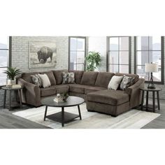 a living room with a sectional couch and coffee table in front of a brick wall