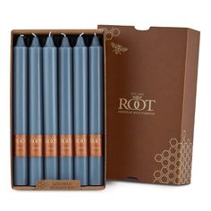 six blue candles in a cardboard box next to a brown box with the word root on it