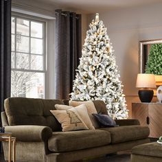 a living room filled with furniture and a white christmas tree in the middle of it