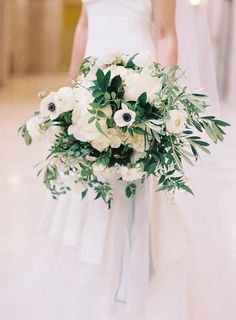 a bridal holding a bouquet of white flowers and greenery