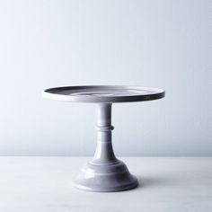 a white cake plate sitting on top of a table next to a wall and floor