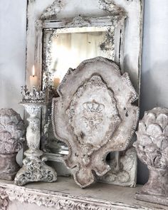 an old mirror sitting on top of a mantle next to some statues and candles in front of it