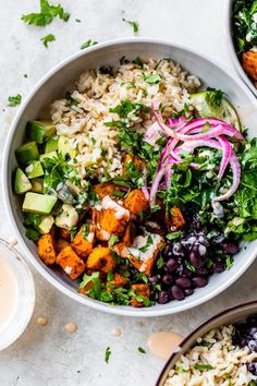 two bowls filled with rice, beans and veggies on top of a table