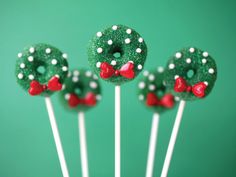 four green donuts decorated with white and red polka dots on top of each other