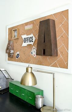 a cork board mounted to the side of a wall next to a lamp and other items