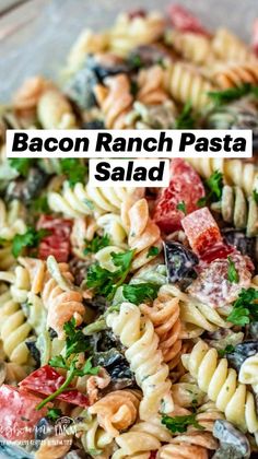 pasta salad with tomatoes, olives, and parsley in a glass bowl on a table