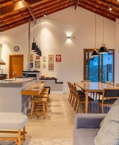 an open concept kitchen and dining area with wood beams on the ceiling, along with modern furniture