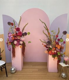 two pink vases with flowers in them sitting on a wooden floor next to each other