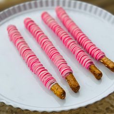 four pink and white candy sticks on a plate