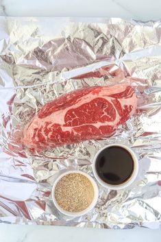 steak on tin foil with two cups of coffee and seasoning in front of it