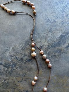 I made this necklace using bronze colored leather, strung with different sizes Baroque pearls, tied together about 18" down, total length is 26".  All my jewelry comes in a hand painted box. My jewelry is unique, no two pieces are alike but some are similar.  I love using different metals, sterling silver, brass and copper; and mixing various beads, pearls, semi-precious, glass, wood, antique and repurposed.   💙 Elegant Brown Necklace With Adjustable Cord, Adjustable Beaded Brown Lariat Necklace, Adjustable Brown Lariat Necklaces, Brown Lariat Jewelry With Adjustable Cord, Adjustable Brown Beaded Lariat Necklace, Adjustable Beaded Lariat Pearl Necklace, Adjustable Brown Long Lariat Necklace, Brown Lariat Necklace For Gift, Adjustable Hand-strung Lariat Necklace