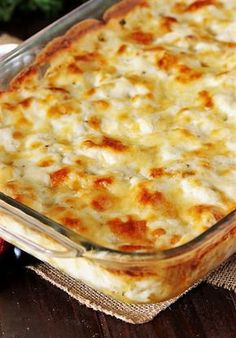 a casserole dish with cheese and vegetables in it on a wooden table next to other dishes