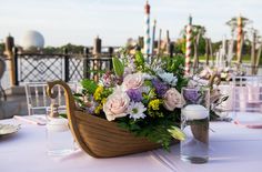 there is a boat with flowers in it sitting on the table at this wedding reception