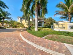 the entrance to an apartment complex with palm trees in front of it and a sign that says attitude