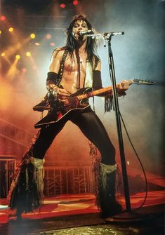 a man with long hair holding a guitar on stage