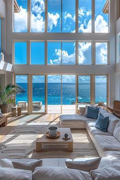 a living room with large windows overlooking the ocean and sky is featured in this photo