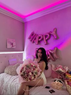 a woman sitting on top of a bed with flowers in her hand and balloons above her head