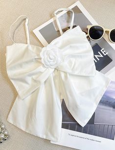 a white top with a flower on it and sunglasses laying next to some other items