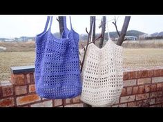 two crocheted bags hanging on a brick wall next to a tree with no leaves