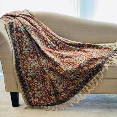 a couch with a blanket draped over it's back on top of carpeted floor