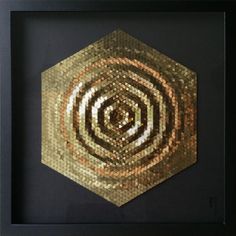 a gold and black mosaic art piece in a frame on the wall above it is an image of a hexagonal object