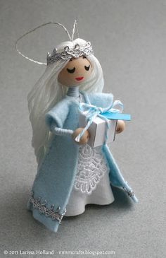 a small doll holding a gift box with a tiara on it's head