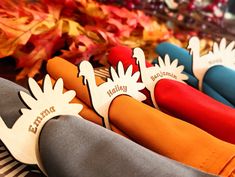 several different colored knives are lined up on a table with autumn leaves in the background