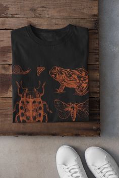 Thanks for stopping by! Cottagecore Snails, Frogs and Bugs T-shirt Printed on a super soft, cotton tee Dispatched in 5 working days or sooner Unisex Free UK delivery Material: 100% ringspun cotton. Chest (to fit): S  34/36   M  38   L  40/42   XL  44/46   XXL  48/50 ECO-FRIENDLY Each garment is made to order, reducing extra material and energy that would be otherwise wasted We use DTG printing process which is easier on the environment than screen-printing Our ink is bright and also eco-friendly Bleach Bug Shirt, Goth Cottagecore Aesthetic, Insect Shirt, Bleach Tshirt, Frog Tshirt, Fairycore Clothing, Bleach T Shirt