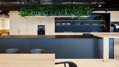 an open kitchen and dining area with plants hanging from the ceiling, while people walk by