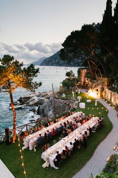 an outdoor dinner is set up on the lawn by the water