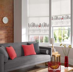 a living room filled with furniture and windows covered in roman blind shades on top of brick walls