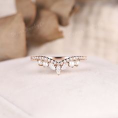 a diamond and pearl ring sitting on top of a pillow