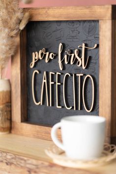 a coffee cup sitting on top of a table next to a sign that says per first cafecito