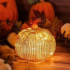 a lighted pumpkin sitting on top of a wooden table