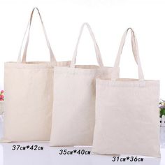 three canvas bags are shown side by side, one is white and the other is beige