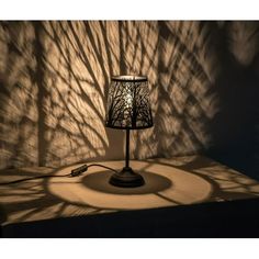 a lamp that is sitting on a table in front of a wall with shadow cast on it