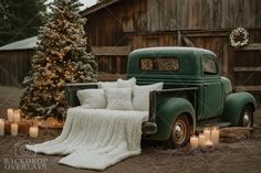 an old green truck is parked in front of a christmas tree with candles around it